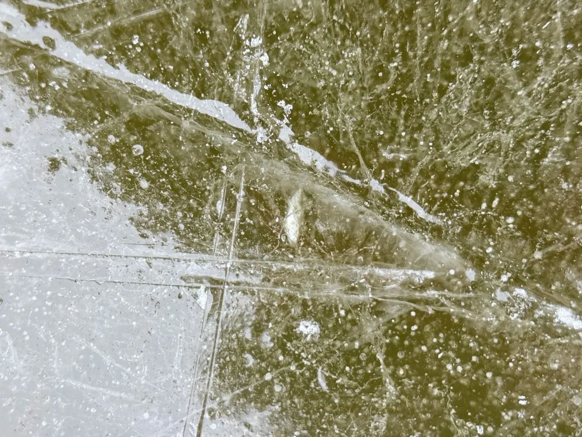 Nahaufnahme einer rissigen Eisfläche mit eingeschlossenen Luftblasen